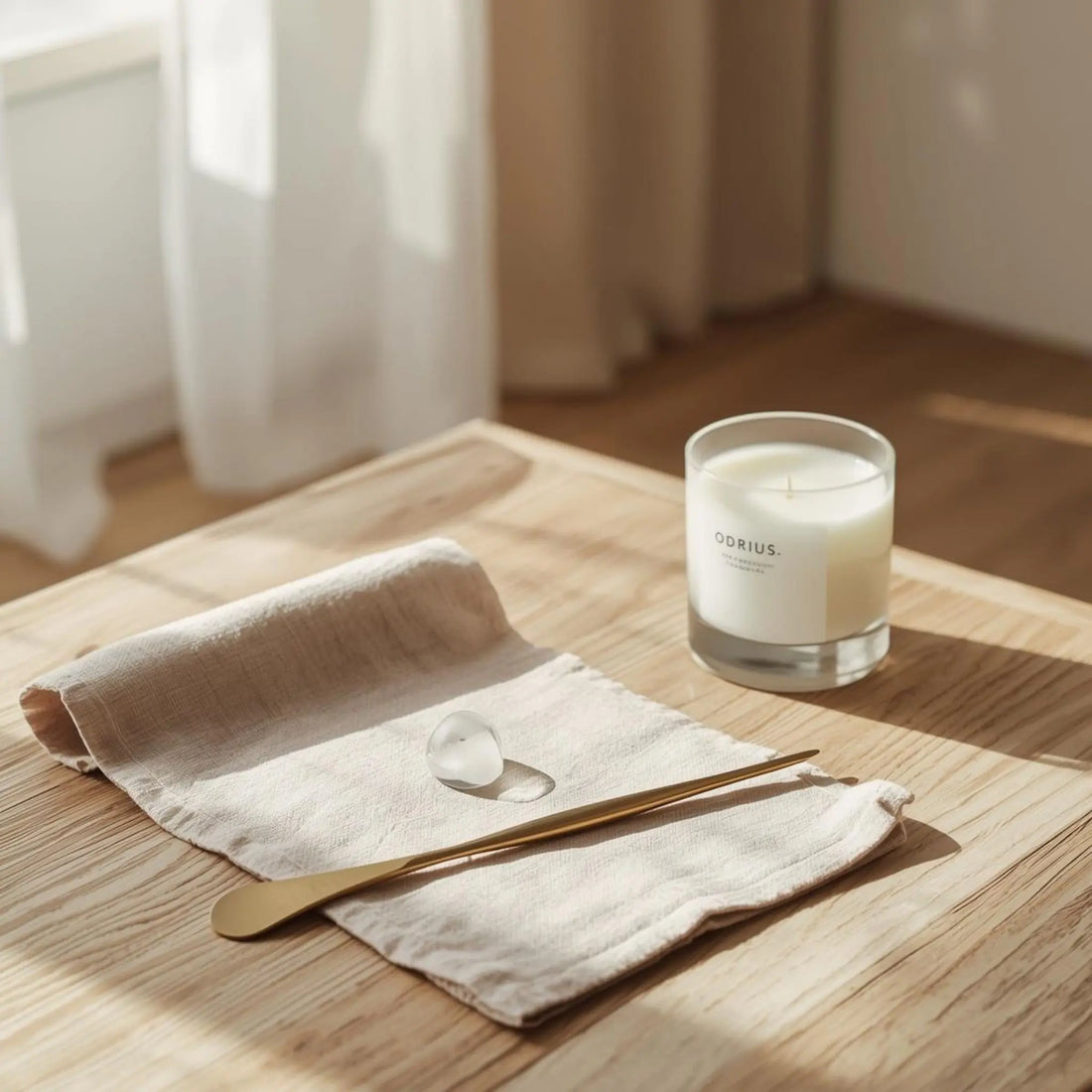 Lüks Belçika keteni üzerindeki mum lekesini çıkarmak için hazırlanan, şık Odrius mumu ve pirinç temizleme aleti ile minimalist sunum.